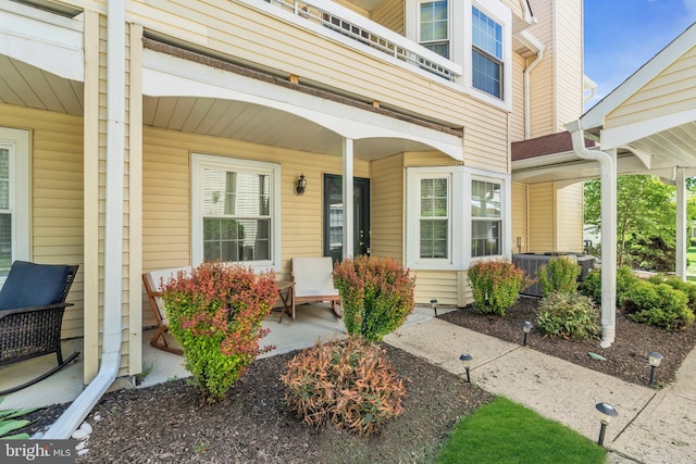 view of exterior entry with covered porch and central AC
