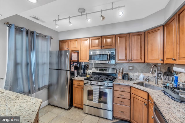 kitchen featuring decorative backsplash, brown cabinetry, visible vents, appliances with stainless steel finishes, and a sink
