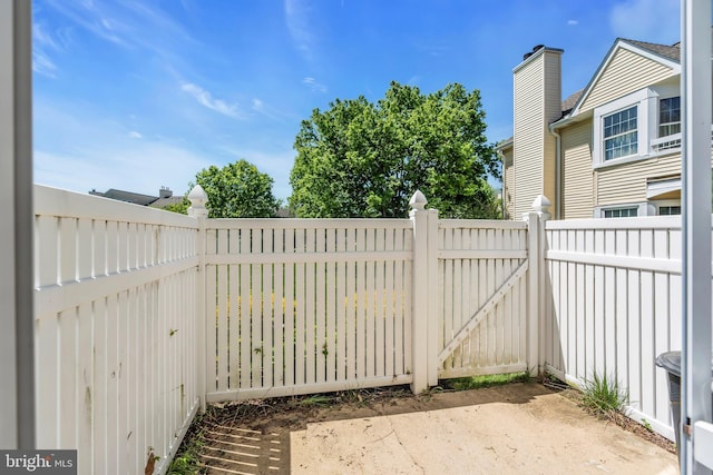 view of gate with fence and a patio