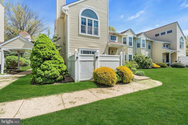 view of front facade with a chimney, fence private yard, and a front lawn