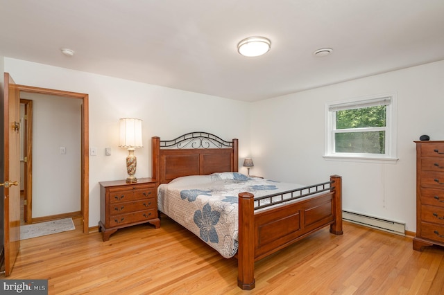 bedroom featuring light wood-style floors and a baseboard heating unit