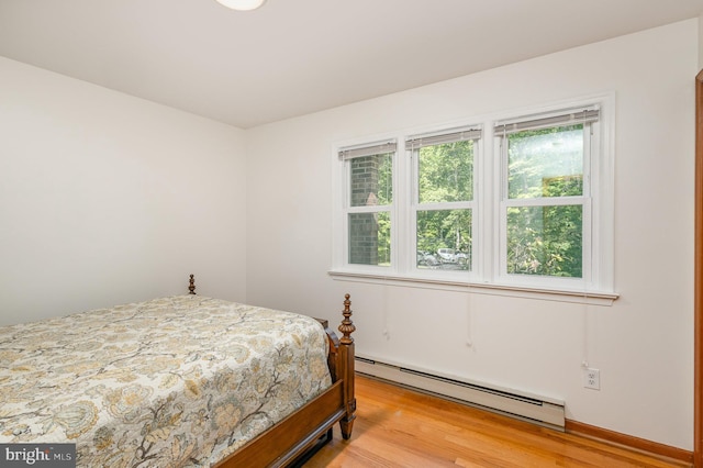 bedroom with a baseboard radiator and light wood-style flooring