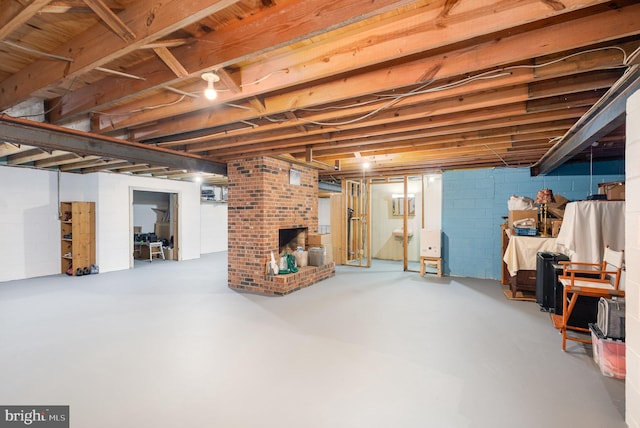 unfinished basement with a fireplace and concrete block wall