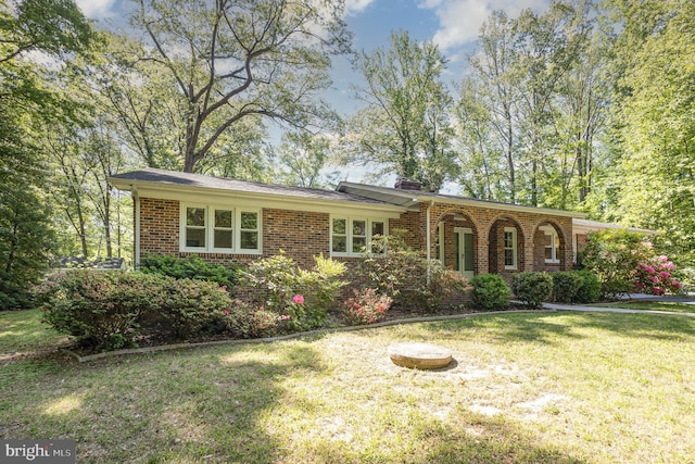 ranch-style house featuring brick siding, a chimney, and a front lawn