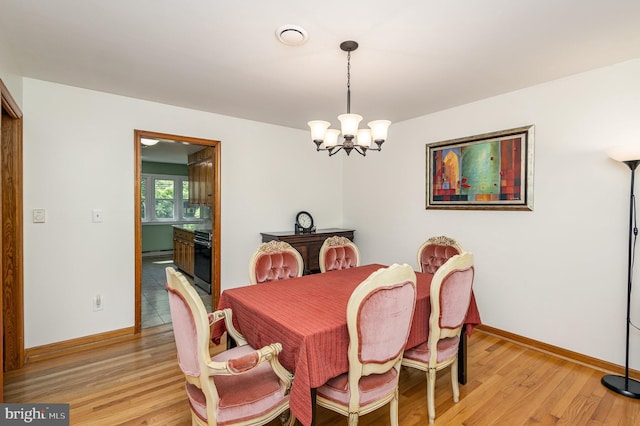 dining room with a baseboard heating unit, baseboards, a notable chandelier, and light wood-type flooring