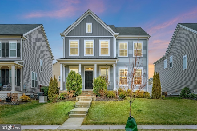 traditional-style home featuring a lawn, board and batten siding, central air condition unit, and covered porch