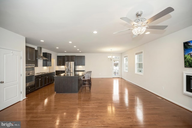 living area with dark wood-type flooring, recessed lighting, baseboards, and ceiling fan with notable chandelier