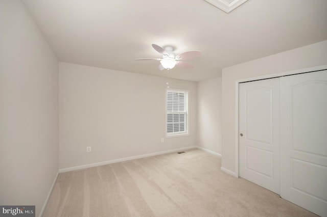 unfurnished bedroom featuring baseboards, light colored carpet, ceiling fan, and a closet