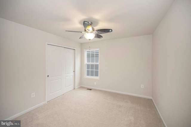 unfurnished bedroom featuring visible vents, a closet, light carpet, baseboards, and a ceiling fan