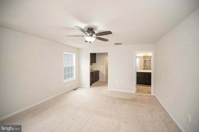 unfurnished bedroom with baseboards, light carpet, connected bathroom, and visible vents