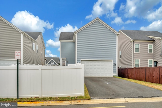 view of side of property with an attached garage, fence, and driveway