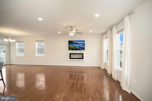 unfurnished living room with baseboards, recessed lighting, a glass covered fireplace, and wood finished floors