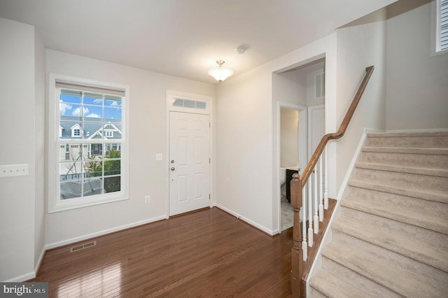 entryway with stairs, baseboards, visible vents, and dark wood-type flooring
