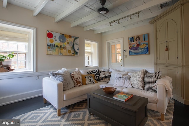 living room with wainscoting, a decorative wall, beam ceiling, and wood ceiling