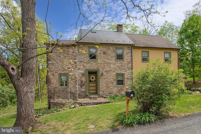 view of front of property with a chimney, a front lawn, and stone siding