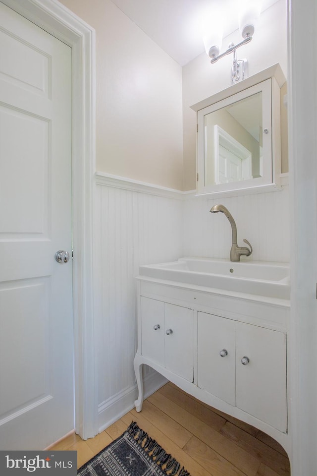 bathroom featuring vanity, wainscoting, and wood finished floors