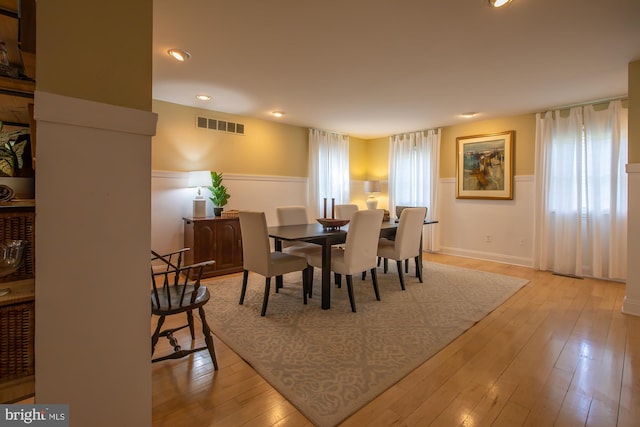dining room featuring visible vents, recessed lighting, light wood finished floors, and a wainscoted wall