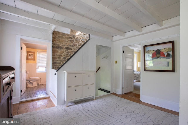 interior space featuring vaulted ceiling with beams, baseboards, and light wood-style flooring