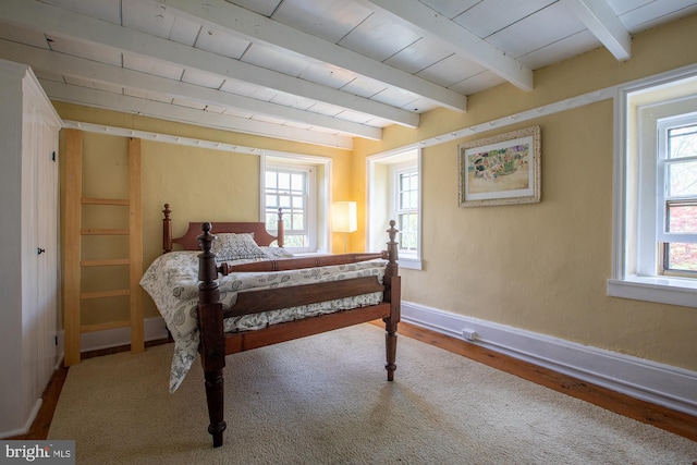 bedroom featuring baseboards, wood finished floors, beam ceiling, and wooden ceiling