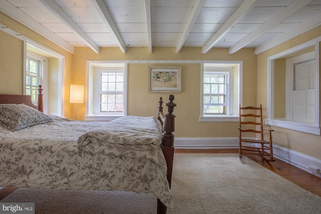 bedroom featuring beamed ceiling, baseboards, and wood finished floors