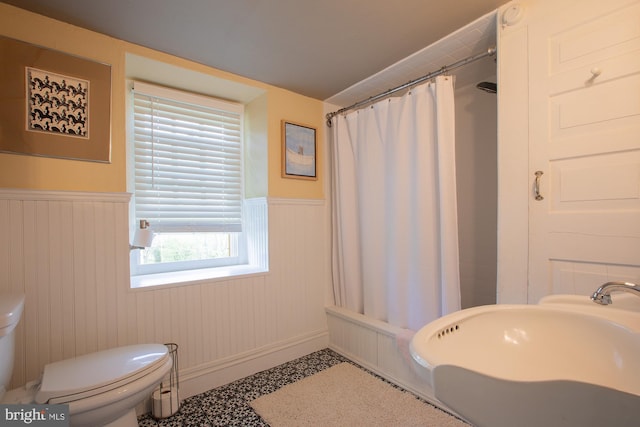 full bathroom featuring a sink, a wainscoted wall, toilet, and shower / tub combo