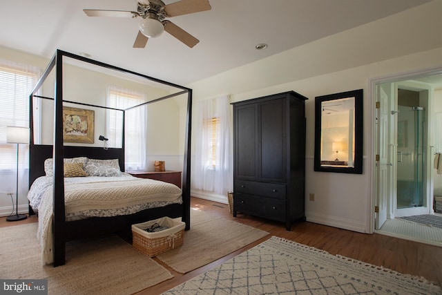 bedroom with baseboards, a ceiling fan, ensuite bath, and wood finished floors