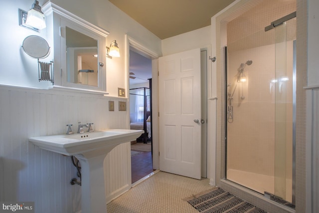 ensuite bathroom with connected bathroom, wainscoting, and a shower stall