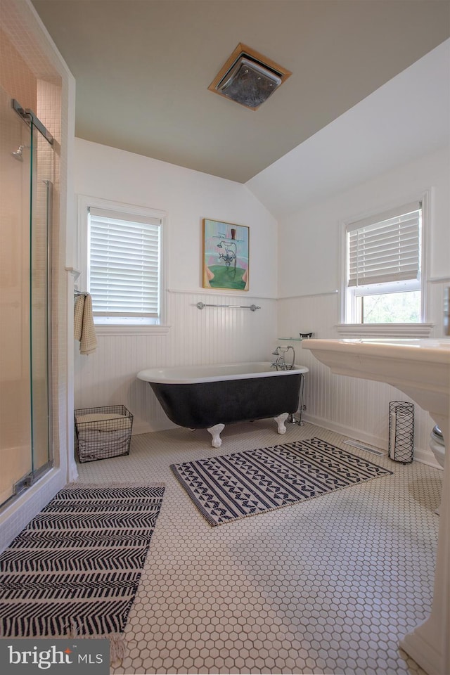 full bathroom with a stall shower, a freestanding tub, a wealth of natural light, and a wainscoted wall