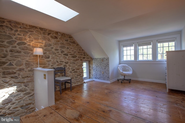 additional living space with plenty of natural light, vaulted ceiling with skylight, and hardwood / wood-style flooring