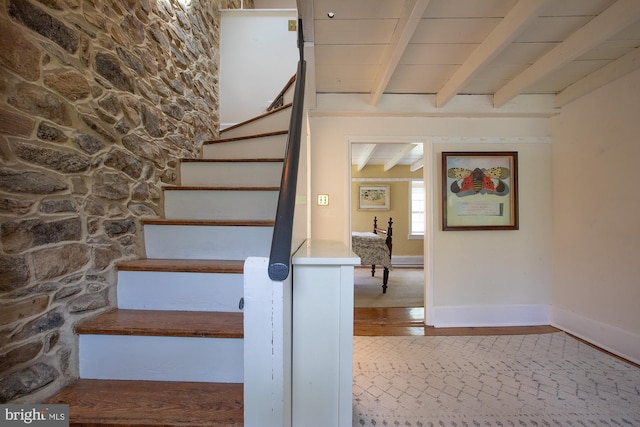 staircase with baseboards and beam ceiling