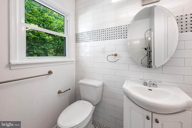 bathroom with toilet, vanity, and tile walls