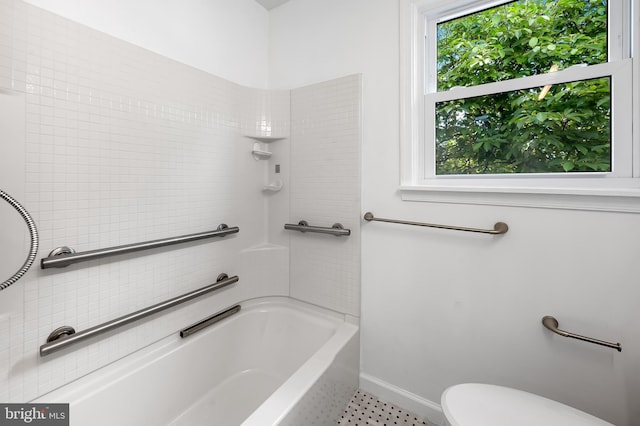 bathroom with toilet, baseboards, and  shower combination