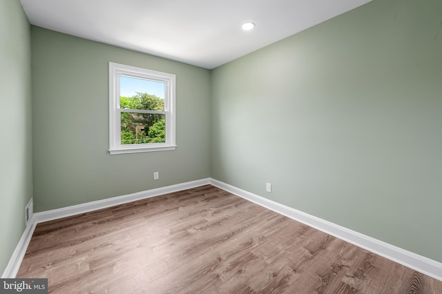 spare room with baseboards, wood finished floors, and recessed lighting