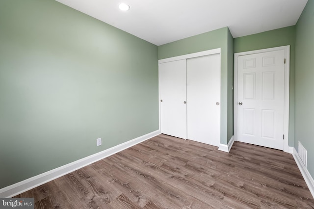 unfurnished bedroom with baseboards, wood finished floors, a closet, and recessed lighting