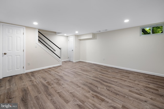 basement featuring wood finished floors, baseboards, recessed lighting, and stairway