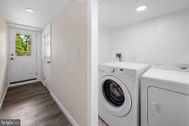 clothes washing area featuring washing machine and dryer, baseboards, and wood finished floors