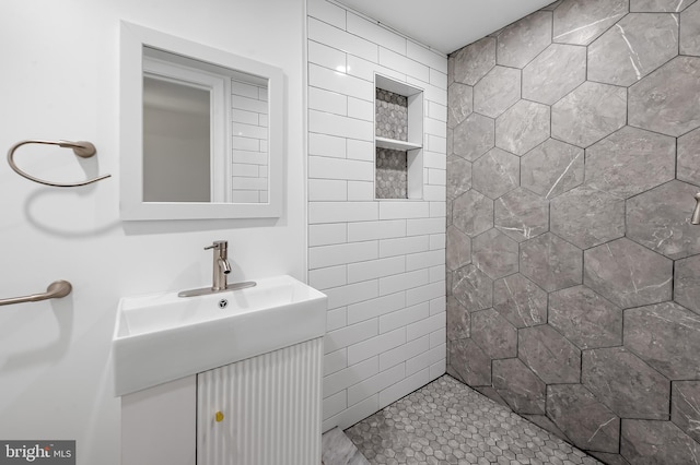 full bath with tiled shower and vanity