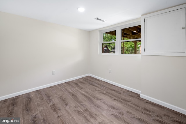 spare room with baseboards and wood finished floors
