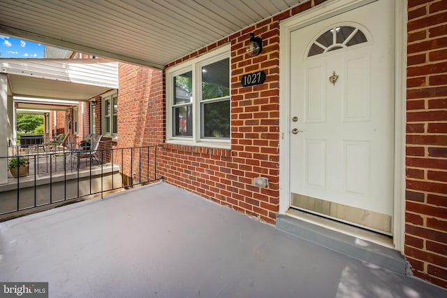 doorway to property featuring brick siding and a porch