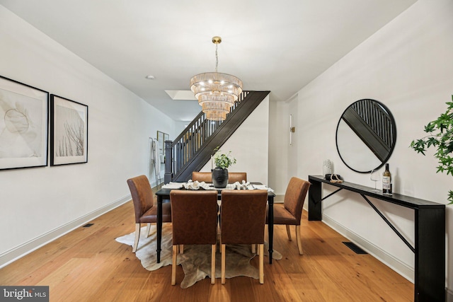 dining room with stairway, a chandelier, light wood-style floors, and baseboards