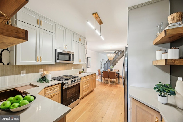 kitchen with stainless steel appliances, open shelves, light countertops, and light wood finished floors