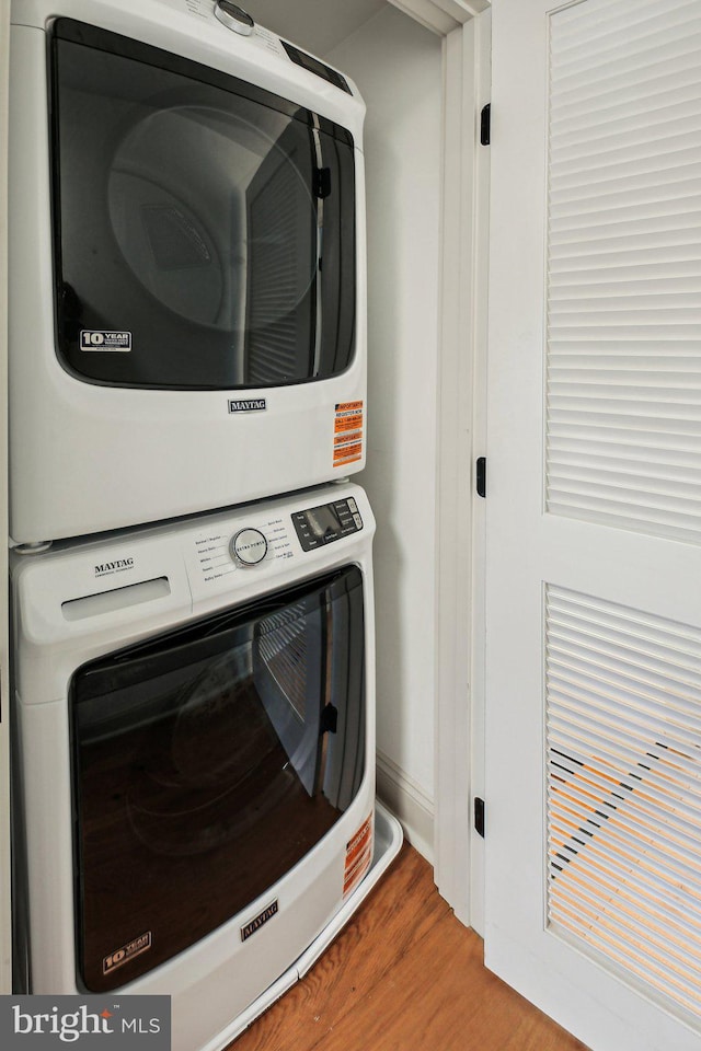 laundry room with stacked washer / drying machine and wood finished floors