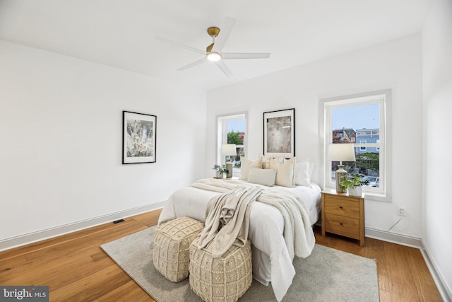 bedroom with wood finished floors, baseboards, and a ceiling fan