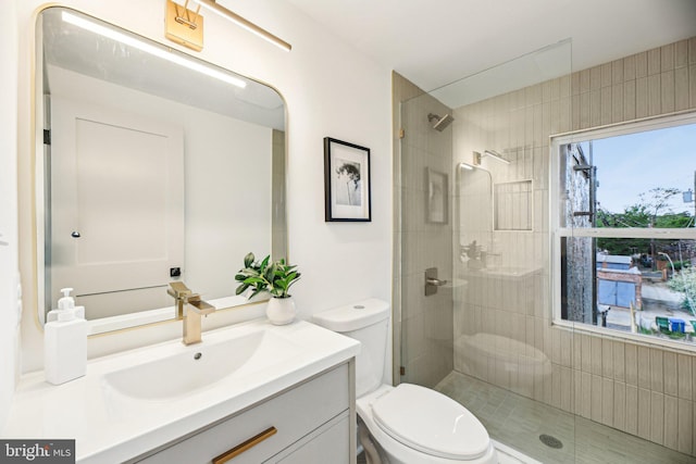 bathroom featuring toilet, tiled shower, and vanity