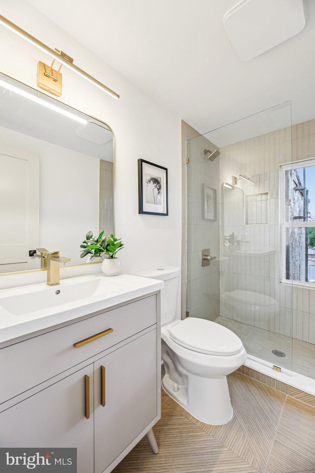 bathroom with walk in shower, toilet, vanity, and tile patterned flooring