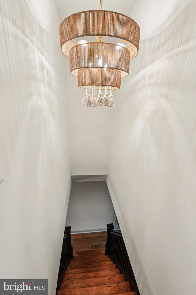 stairway featuring a chandelier, wood finished floors, and baseboards