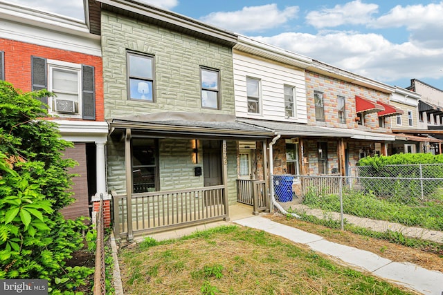view of property featuring a porch, fence, stone siding, and cooling unit