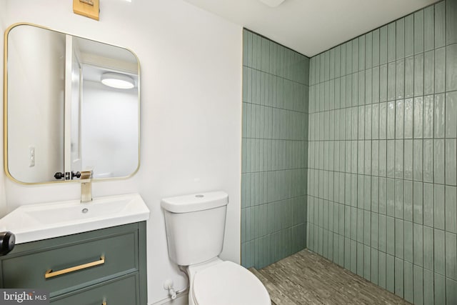 full bath with toilet, vanity, and a tile shower