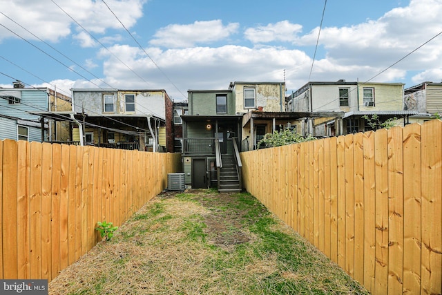 back of house with central air condition unit, a fenced backyard, and stairway