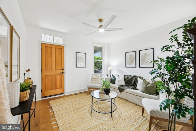 living area with ceiling fan, wood-type flooring, and baseboards